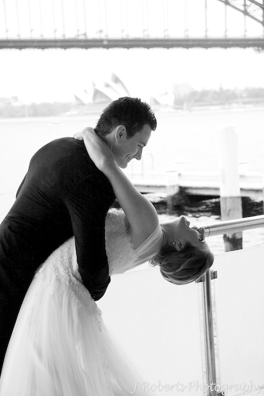 Groom dipping the bride in front of the Sydney Harbour Bridge - wedding photography sydney